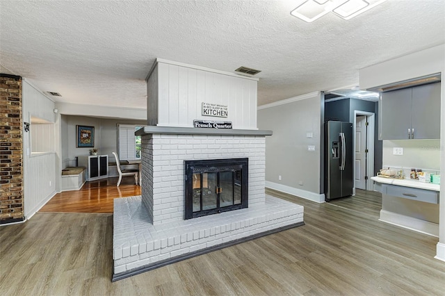 418 N Rd, Lakeland, FL 33809 - living room featuring wood finished floors, a brick fireplace, baseboards, a textured ceiling, and crown molding