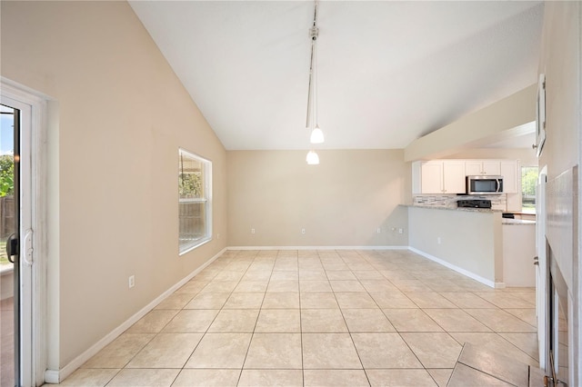 630 Heather Glen Loop, Winter Haven, FL 33884 - kitchen featuring stainless steel microwave, lofted ceiling, white cabinets, decorative backsplash, and light tile patterned floors