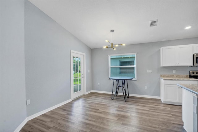 648 Lorient Dr, Eagle Lake, FL 33839 - kitchen featuring a chandelier, light wood-style flooring, white cabinetry, lofted ceiling, and light stone countertops