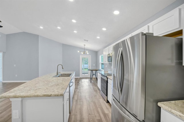 648 Lorient Dr, Eagle Lake, FL 33839 - kitchen with appliances with stainless steel finishes, vaulted ceiling, white cabinetry, light wood-style flooring, and a center island with sink