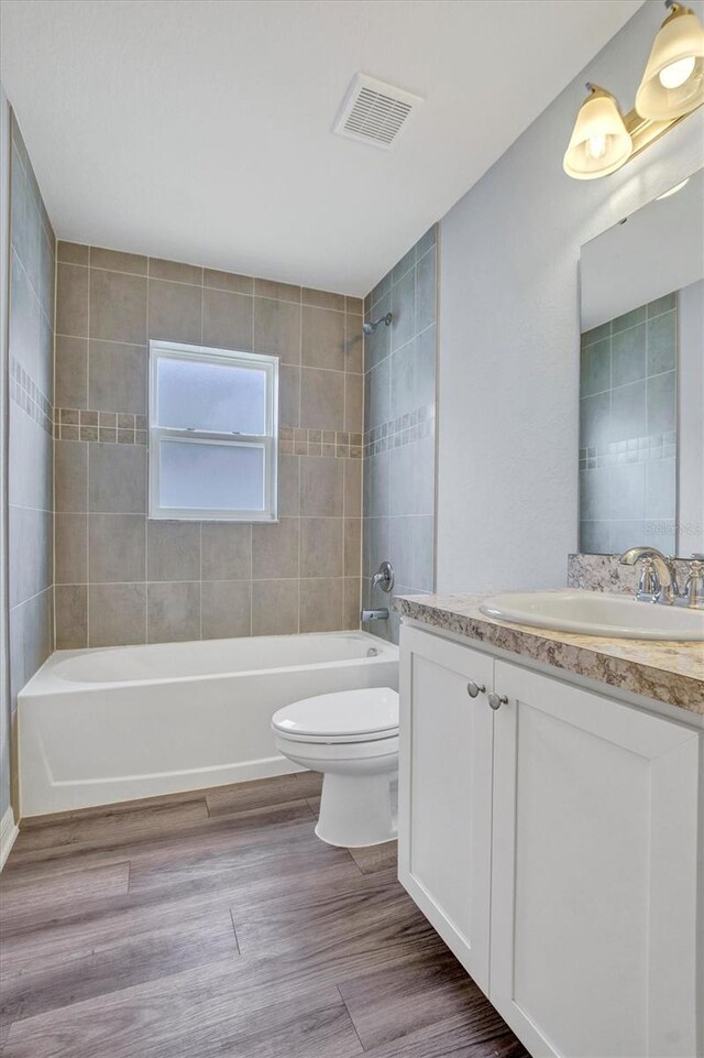 648 Lorient Dr, Eagle Lake, FL 33839 - bathroom featuring vanity, shower / bathtub combination, and wood finished floors