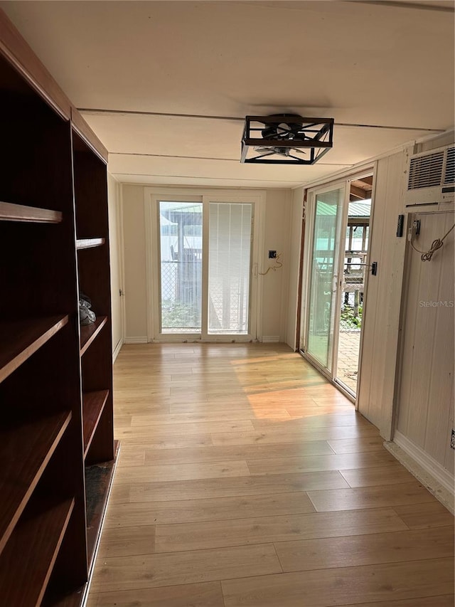 9402 Cat Track Trl, Lake Wales, FL 33898 - unfurnished dining area featuring light wood finished floors, a wall mounted AC, ceiling fan, and baseboards
