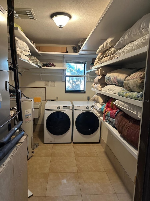 9402 Cat Track Trl, Lake Wales, FL 33898 - washroom with washer and clothes dryer, water heater, a textured ceiling, and light tile patterned floors