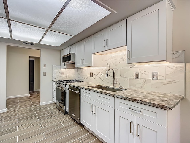 560 Saint Andrews Rd, Winter Haven, FL 33884 - kitchen featuring a sink, appliances with stainless steel finishes, light stone counters, decorative backsplash, and white cabinetry