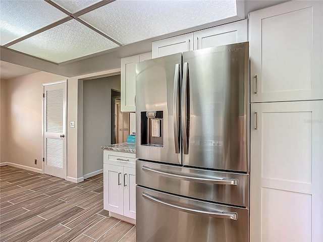560 Saint Andrews Rd, Winter Haven, FL 33884 - kitchen featuring stainless steel fridge, white cabinets, baseboards, and wood tiled floors