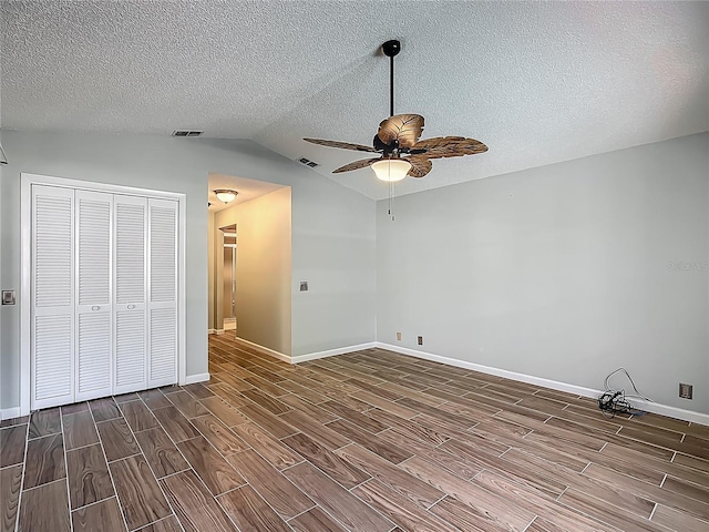 560 Saint Andrews Rd, Winter Haven, FL 33884 - unfurnished bedroom featuring dark wood-style floors, baseboards, vaulted ceiling, a closet, and a textured ceiling
