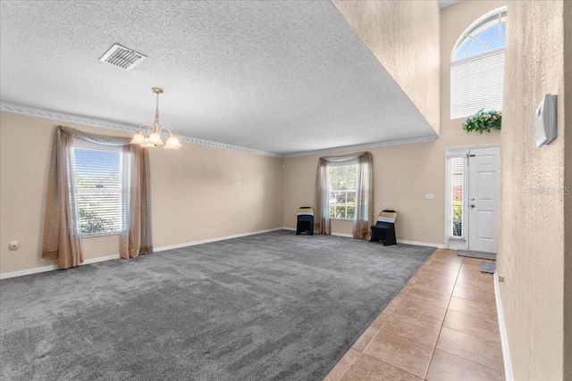 1800 Emily Dr, Winter Haven, FL 33884 - unfurnished living room with a chandelier, ornamental molding, carpet flooring, a textured ceiling, and baseboards