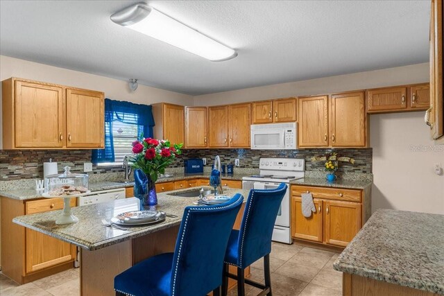 1800 Emily Dr, Winter Haven, FL 33884 - kitchen with white appliances, decorative backsplash, a sink, a breakfast bar, and light stone counters