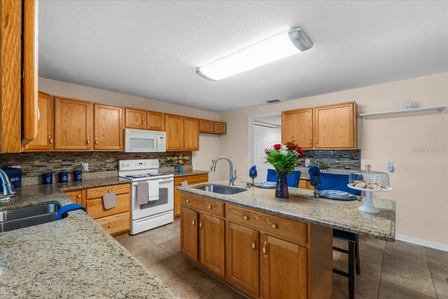 1800 Emily Dr, Winter Haven, FL 33884 - kitchen featuring white appliances, a sink, tasteful backsplash, brown cabinetry, and a textured ceiling