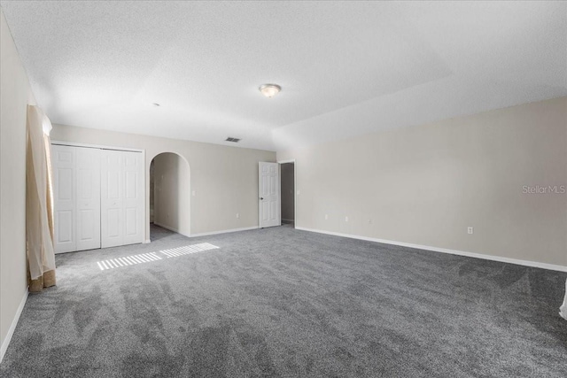 1800 Emily Dr, Winter Haven, FL 33884 - unfurnished bedroom with carpet, arched walkways, baseboards, and a textured ceiling