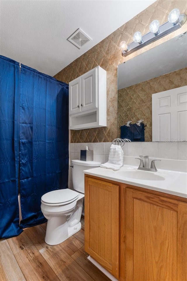 1800 Emily Dr, Winter Haven, FL 33884 - full bath featuring tile walls, toilet, wood finished floors, vanity, and a shower with shower curtain