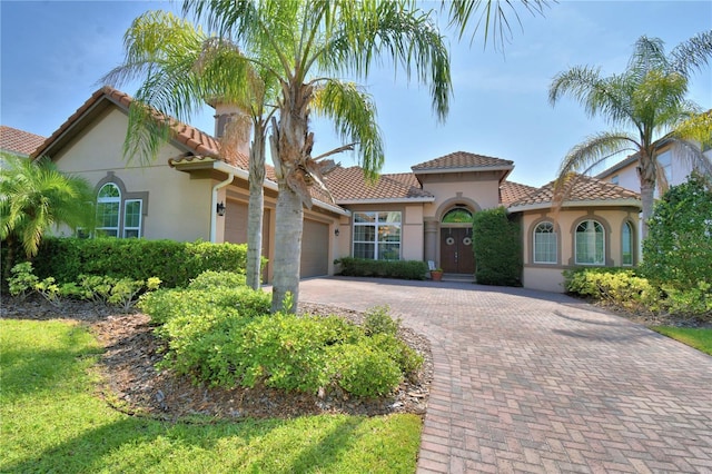 2340 Pinehurst Ct, Davenport, FL 33837 - mediterranean / spanish-style house featuring stucco siding, a garage, decorative driveway, and a tile roof