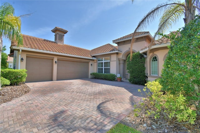 2340 Pinehurst Ct, Davenport, FL 33837 - mediterranean / spanish-style house featuring a tiled roof, an attached garage, stucco siding, and decorative driveway
