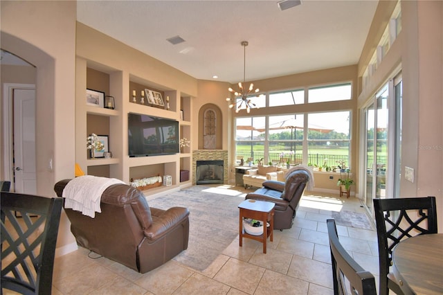 2340 Pinehurst Ct, Davenport, FL 33837 - living room featuring built in shelves, light tile patterned floors, a chandelier, a stone fireplace, and arched walkways
