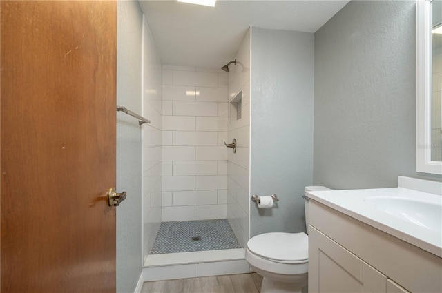 5102 Village Ct Unit E-2, Lake Wales, FL 33898 - full bathroom with a tile shower, toilet, vanity, wood finished floors, and a textured wall