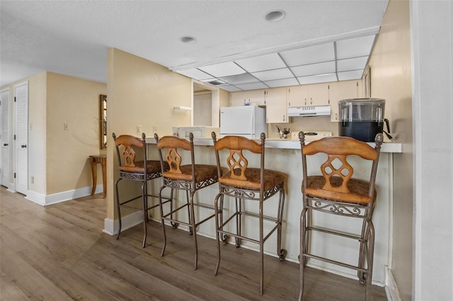 713 Olde Camelot Cir Unit 3303-4, Haines City, FL 33844 - kitchen featuring freestanding refrigerator, wood finished floors, baseboards, a peninsula, and a drop ceiling