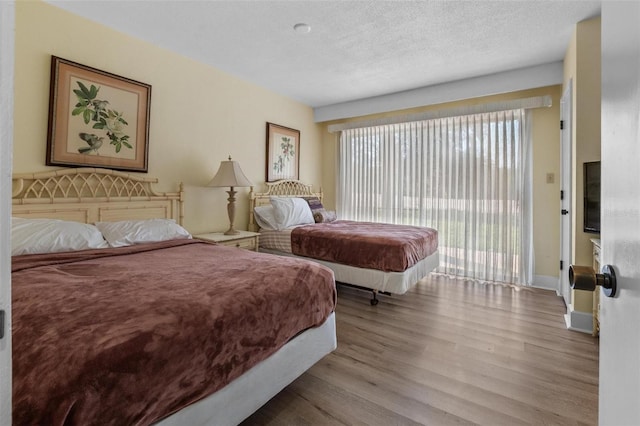 713 Olde Camelot Cir Unit 3303-4, Haines City, FL 33844 - bedroom featuring wood finished floors, access to exterior, and a textured ceiling
