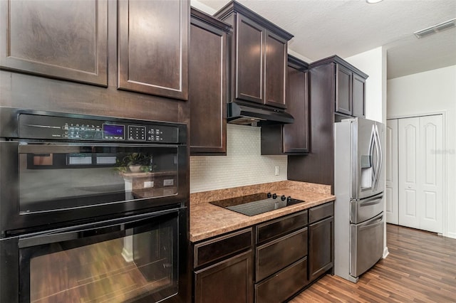 122 Port Royal Ct, Sebastian, FL 32958 - kitchen with black appliances, under cabinet range hood, wood finished floors, backsplash, and dark brown cabinetry