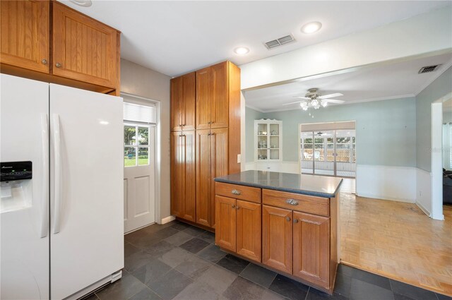 961 Oleander Dr SE, Winter Haven, FL 33880 - kitchen with white fridge with ice dispenser, a ceiling fan, brown cabinets, ornamental molding, and dark countertops