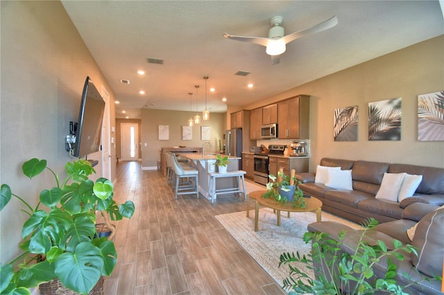 1100 Sugarwood St, Davenport, FL 33837 - living area with light wood finished floors, ceiling fan, recessed lighting, and baseboards