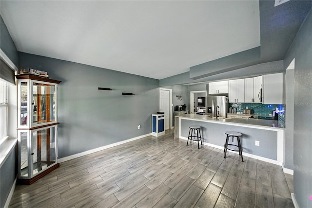 1140 W Seminole Trl, Bartow, FL 33830 - kitchen with stainless steel fridge, wood finished floors, white cabinetry, a breakfast bar, and a peninsula
