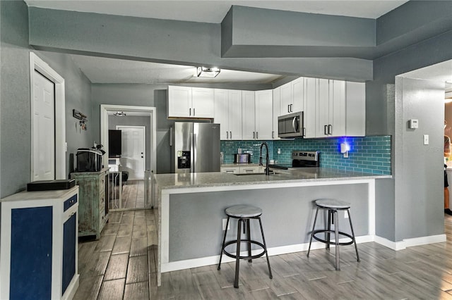 1140 W Seminole Trl, Bartow, FL 33830 - kitchen featuring stainless steel appliances, wood finish floors, a peninsula, a kitchen breakfast bar, and decorative backsplash