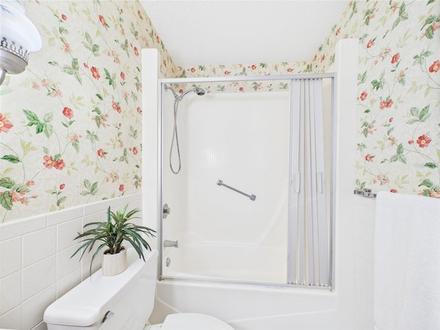 2700 Bayshore Blvd Unit 3210, Dunedin, FL 34698 - full bathroom with wallpapered walls, toilet, wainscoting, combined bath / shower with glass door, and tile walls