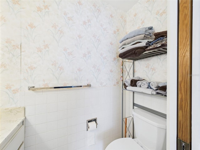 2700 Bayshore Blvd Unit 3210, Dunedin, FL 34698 - half bath featuring wallpapered walls, toilet, vanity, tile walls, and wainscoting