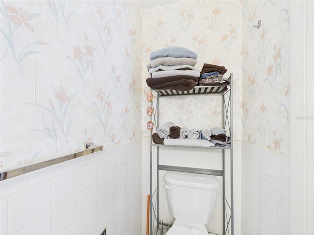 2700 Bayshore Blvd Unit 3210, Dunedin, FL 34698 - half bathroom with wallpapered walls, toilet, wainscoting, and tile walls