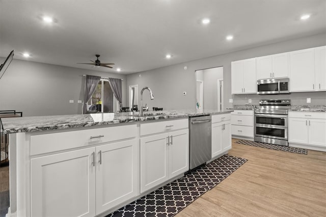 1081 Sandpiper Loop, Winter Haven, FL 33881 - kitchen with appliances with stainless steel finishes, a sink, ceiling fan, light wood finished floors, and white cabinetry