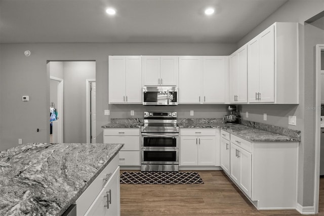 1081 Sandpiper Loop, Winter Haven, FL 33881 - kitchen featuring stainless steel appliances, wood finished floors, white cabinetry, light stone counters, and recessed lighting