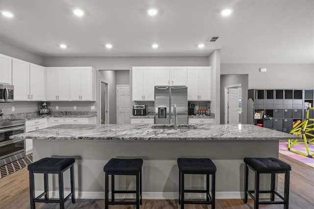 1081 Sandpiper Loop, Winter Haven, FL 33881 - kitchen with appliances with stainless steel finishes, a sink, a breakfast bar area, white cabinets, and a large island with sink