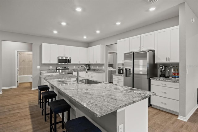 1081 Sandpiper Loop, Winter Haven, FL 33881 - kitchen featuring stainless steel appliances, a sink, a breakfast bar area, baseboards, and white cabinets