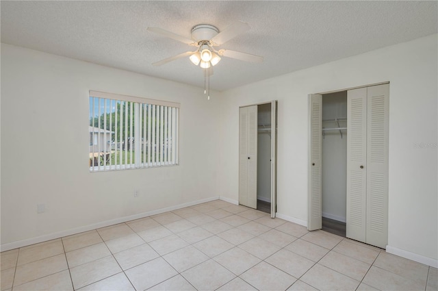 299 Winter Ridge Blvd Unit 299, Winter Haven, FL 33881 - unfurnished bedroom with two closets, a textured ceiling, a ceiling fan, baseboards, and light tile patterned floors