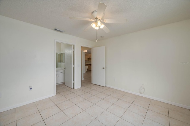 299 Winter Ridge Blvd Unit 299, Winter Haven, FL 33881 - unfurnished bedroom with light tile patterned flooring, a textured ceiling, baseboards, a ceiling fan, and ensuite bathroom
