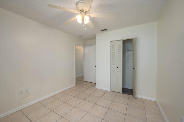 299 Winter Ridge Blvd Unit 299, Winter Haven, FL 33881 - unfurnished bedroom featuring light tile patterned floors, a textured ceiling, a closet, baseboards, and a ceiling fan
