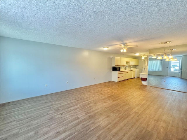 254 Winter Ridge Blvd Unit 254, Winter Haven, FL 33881 - unfurnished living room with light wood-type flooring, a textured ceiling, a chandelier, ceiling fan, and a sink
