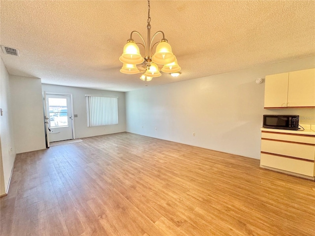254 Winter Ridge Blvd Unit 254, Winter Haven, FL 33881 - unfurnished living room with a chandelier, light wood finished floors, and a textured ceiling