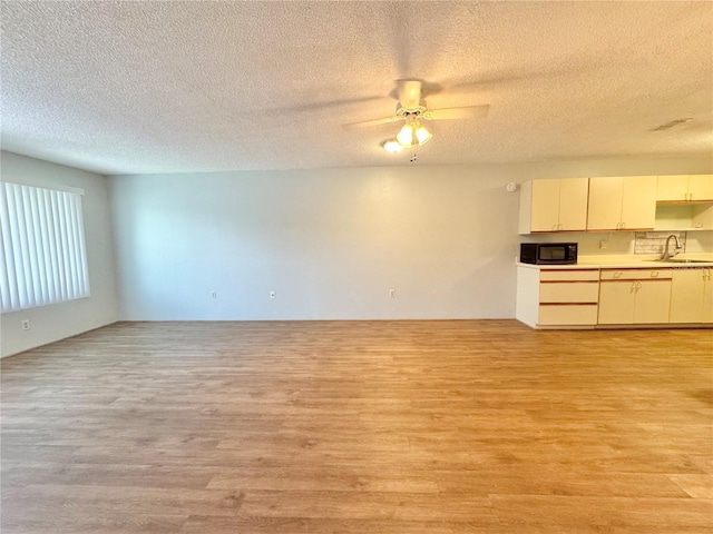 254 Winter Ridge Blvd Unit 254, Winter Haven, FL 33881 - unfurnished living room with light wood finished floors, ceiling fan, a sink, and a textured ceiling