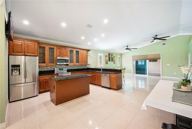 1553 Wright Dr, Lakeland, FL 33805 - kitchen with appliances with stainless steel finishes, a peninsula, a sink, brown cabinetry, and crown molding