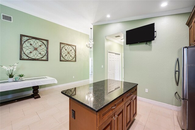 1553 Wright Dr, Lakeland, FL 33805 - kitchen with freestanding refrigerator, ornamental molding, dark stone countertops, a kitchen island, and brown cabinetry