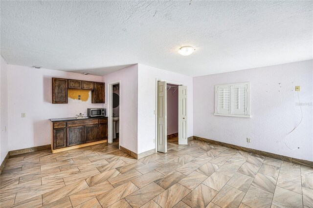 1553 Wright Dr, Lakeland, FL 33805 - kitchen featuring stainless steel microwave, dark brown cabinetry, a textured ceiling, baseboards, and a sink