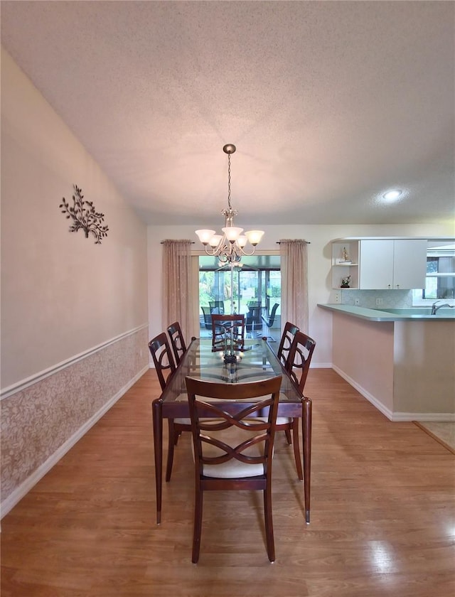 2909 Pine Tree Dr, Edgewater, FL 32141 - dining room with a chandelier, light wood finished floors, a textured ceiling, and baseboards