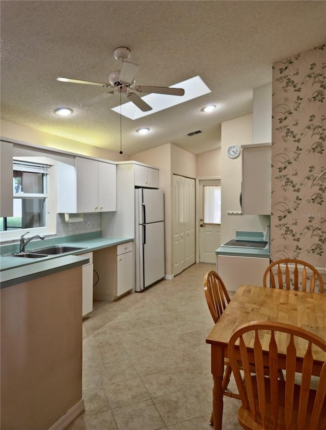 2909 Pine Tree Dr, Edgewater, FL 32141 - kitchen featuring freestanding refrigerator, a sink, a textured ceiling, a ceiling fan, and white cabinetry