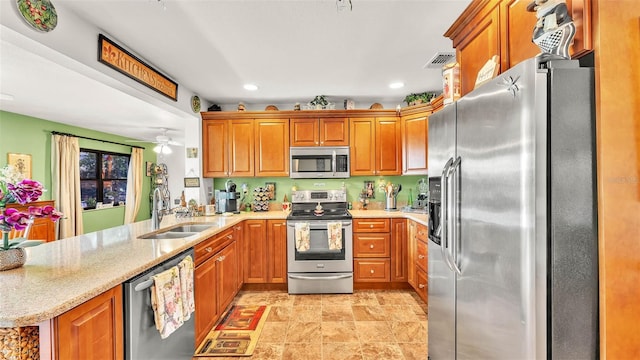 527 Duchess Dr, Lakeland, FL 33803 - kitchen featuring stainless steel appliances, a sink, a peninsula, brown cabinets, and light stone countertops
