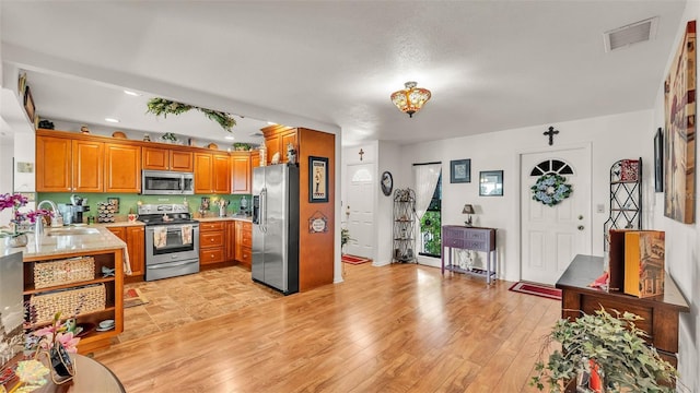 527 Duchess Dr, Lakeland, FL 33803 - kitchen with appliances with stainless steel finishes, a sink, brown cabinets, light countertops, and light wood-style floors