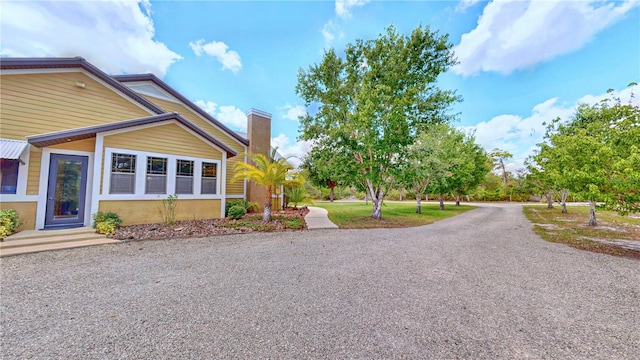 540 Phillips Rd, Sebring, FL 33875 - view of side of home featuring a chimney, stucco siding, and gravel driveway