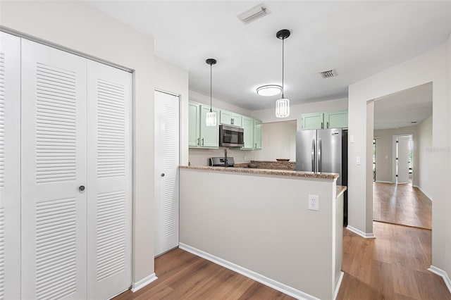 703 Magnolia Pl Unit 703, Winter Haven, FL 33884 - kitchen featuring stainless steel appliances, light wood-style floors, green cabinets, a peninsula, and pendant lighting