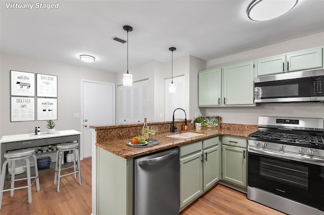 703 Magnolia Pl Unit 703, Winter Haven, FL 33884 - kitchen featuring stainless steel appliances, a sink, green cabinetry, a peninsula, and light wood-style floors