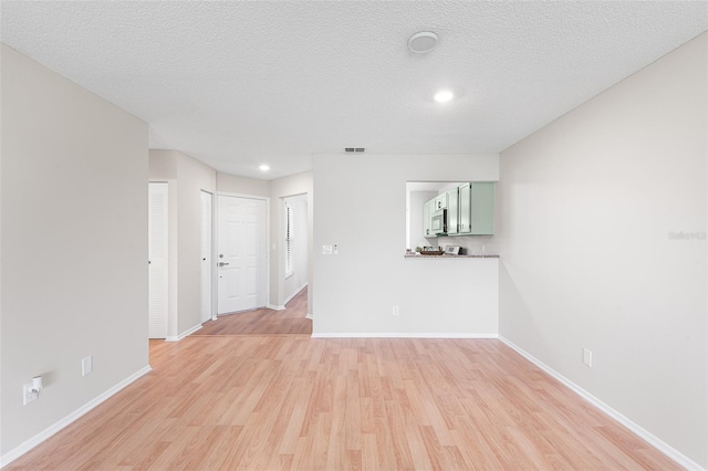 703 Magnolia Pl Unit 703, Winter Haven, FL 33884 - unfurnished living room featuring light wood finished floors, baseboards, recessed lighting, and a textured ceiling